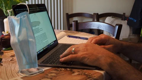 Man at laptop doing smart working with a mask on pc Stock Footage 127708625