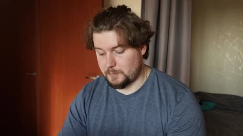 Man with laptop at home, typing on a table in a cozy bedroom, remote work u.. Stock Footage 301949720