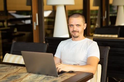 Man with laptop looking in camera while sitting in cafe Stock Photos