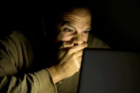 Man on laptop at night looking shocked Stock Photos