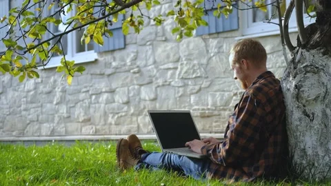 A man with a laptop rejoices at the work done while sitting on the grass Stock Footage 200825919