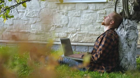 Man with laptop resting sitting under a tree Stock Footage 200825747