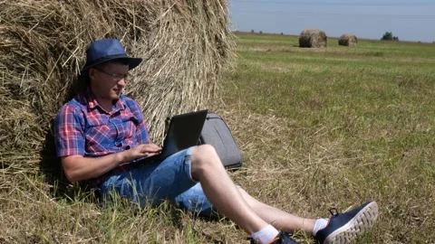 A man with a laptop sits by a haystack. Stock Footage 135594034