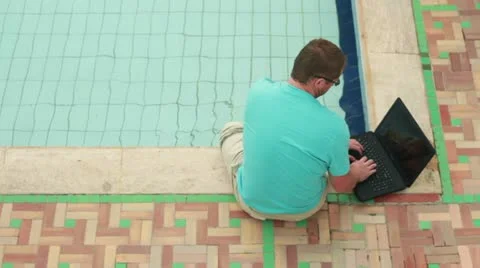 Man with laptop sitting by the pool Vídeos de archivo 10848827