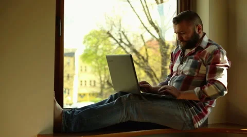 Man with laptop sitting on window Video stock 62824508