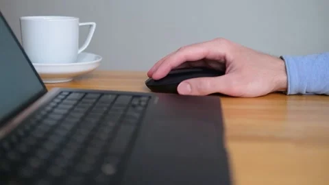 A man with a laptop at a table with a white cup of coffee Stock Footage 204789162