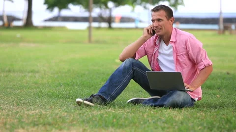Man With Laptop Talking On Mobile Phone In The Park Stock Footage 55612601