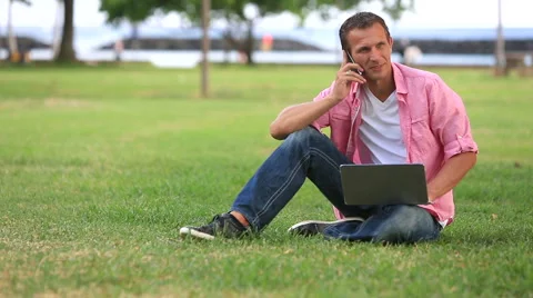 Man With Laptop Talking On Mobile Phone In The Park Stock Footage 55615036
