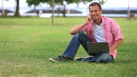 Man With Laptop Talking On Mobile Phone In The Park Stock Footage 55616590