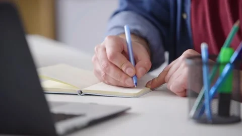 Man at a laptop typing writing in the notebook watch the webinar online course Stock Footage 236588680