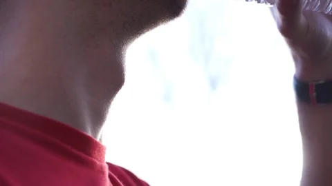 Man with large Adam's apple, drinks water in the sun Stock Footage