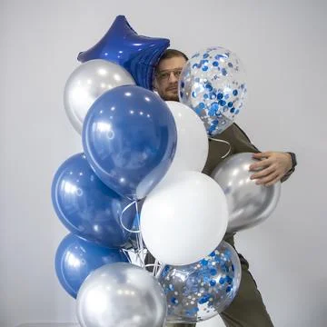 Man with a large bundle of blue, white and silver balloons. Stock Photos