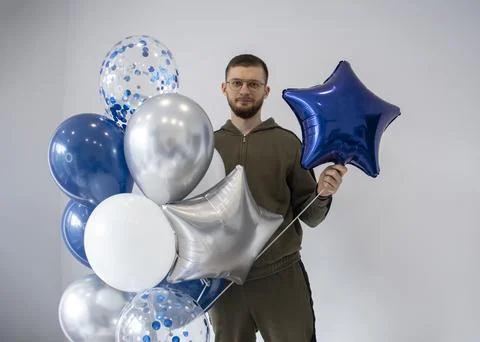 Man with a large bundle of blue, white and silver balloons. Stock Photos