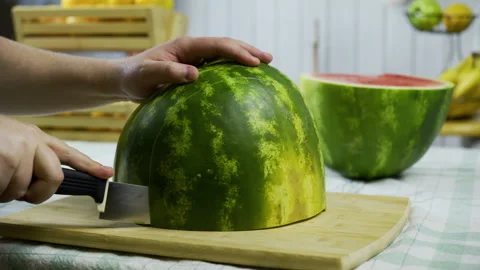 Man with large knife making multiple cuts down the middle of watermelon, Stock Footage 341264245