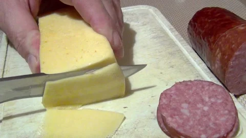 A man with a large sharp knife cuts the hard cheese into pieces on a cutting boa Stock Footage 155426987