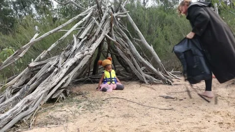 A man in a large water proof jacket carries his bag to a tee pee camp with Vídeo Stock 196233015