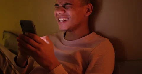 Man laughing and text messaging on mobile phone late night Stock Footage 145290045