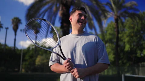 Man laughing while holding tennis racket during casual outdoor practice 스톡 동영상 325338440