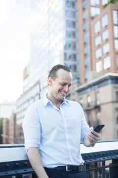 Man laughing while using smartphone outdoors Stock Photos