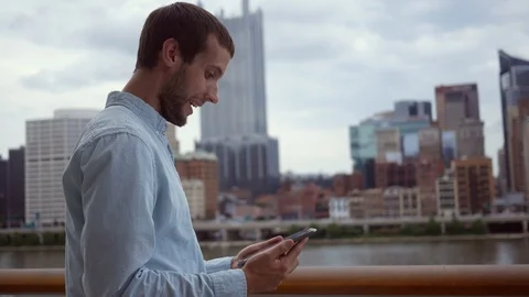 A man laughs at his tablet in a cinematic downtown area Stock Footage 93274596