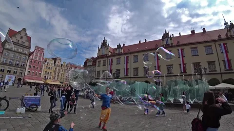 A man launches big soap bubbles entertain people in old city center. Slow motion Stock Footage 101414290