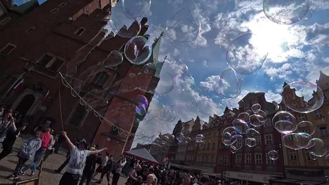 A man launches big soap bubbles entertain people in old city center. Slow motion Stock Footage 101414402