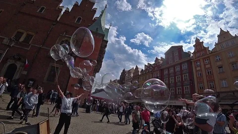 A man launches big soap bubbles entertain tourists in city center. Slow motion Stock Footage 101414575
