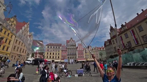 A man launches big soap bubbles entertain tourists in city center. Slow motion Stock Footage 101414577