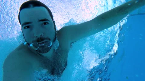 Man launches off diving board into pool and swims underwater Stock Footage 50767200