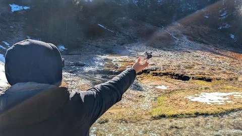 Man launching compact drone over mountain stream in sunny landscape Foto stock
