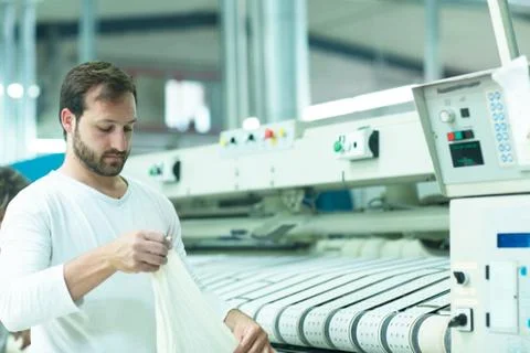 Man in launderette using ironing machine Stock Photos