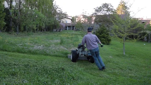Man with lawnmover cutting the grass in a field Stock Footage 107145256
