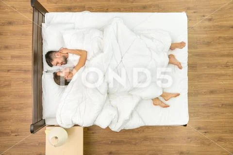 The man lay near a woman on the bed. View from above Stock Photos