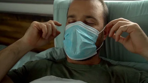 Man laying in bed being removing mask after being sick Video stock 128294310