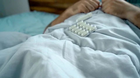 Man laying in bed being sick checking his medicine Stock Footage 128294320