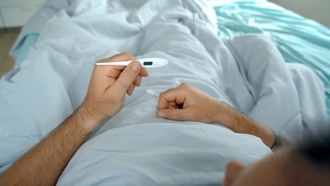 Man laying in bed being sick checking his temperature Video stock 128294457