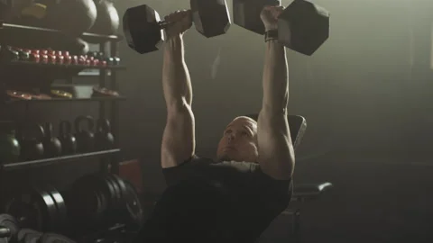 Man laying on bench and lifting dumbbells 스톡 동영상 236191396