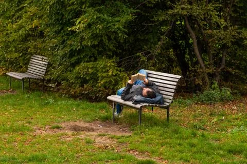 Man is laying on a bench while reading a book on Letna Park in Autumn 2020 on Stock Photos