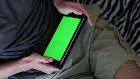 Man is Laying on Couch at Home and Watch on Tablet with Green Screen Stock Footage