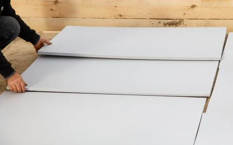 A man is laying down a white sheet on the ground Stock Photos