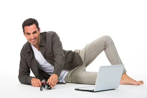 Man laying on the floor, smiling at camera playing with a motorbike scale mod Stock Photos