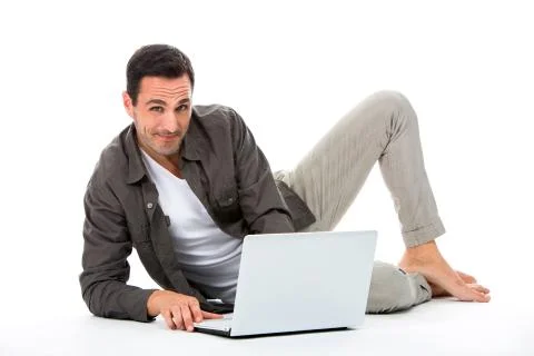 Man laying on the floor, smiling at camera and working with his laptop Stock Photos