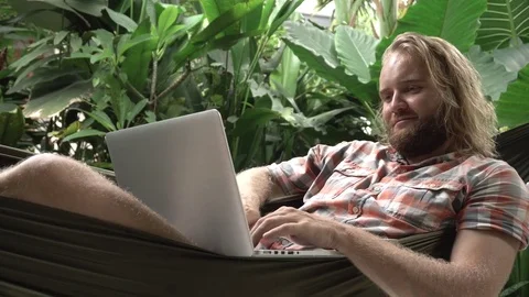 Man laying in hammock using laptop and smiling Stock Footage 84547521