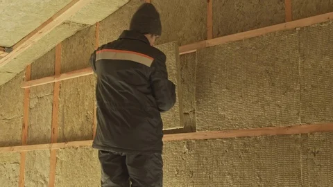 Man laying insulation in a wall under roof Stock Footage 125107019