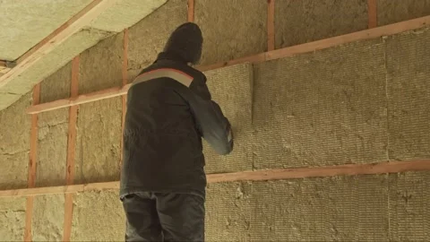 Man laying insulation in a wall under roof Video stock 198432818