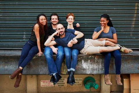 Man laying in laps of friends on loading dock Stock Photos