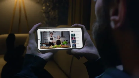 Man laying on sofa watching a cooking tutorial on his smartphone in living .. Vídeo Stock 279594603