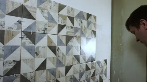A man is laying tiles on a wall. Stock Footage 206138977