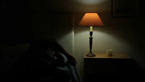 Man lays down in bed and turns off light. Stock Footage 72708581