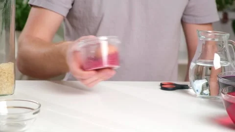 Man lays an egg and shakes container rice color egg. unusual way coloring and Stock Footage 236920853